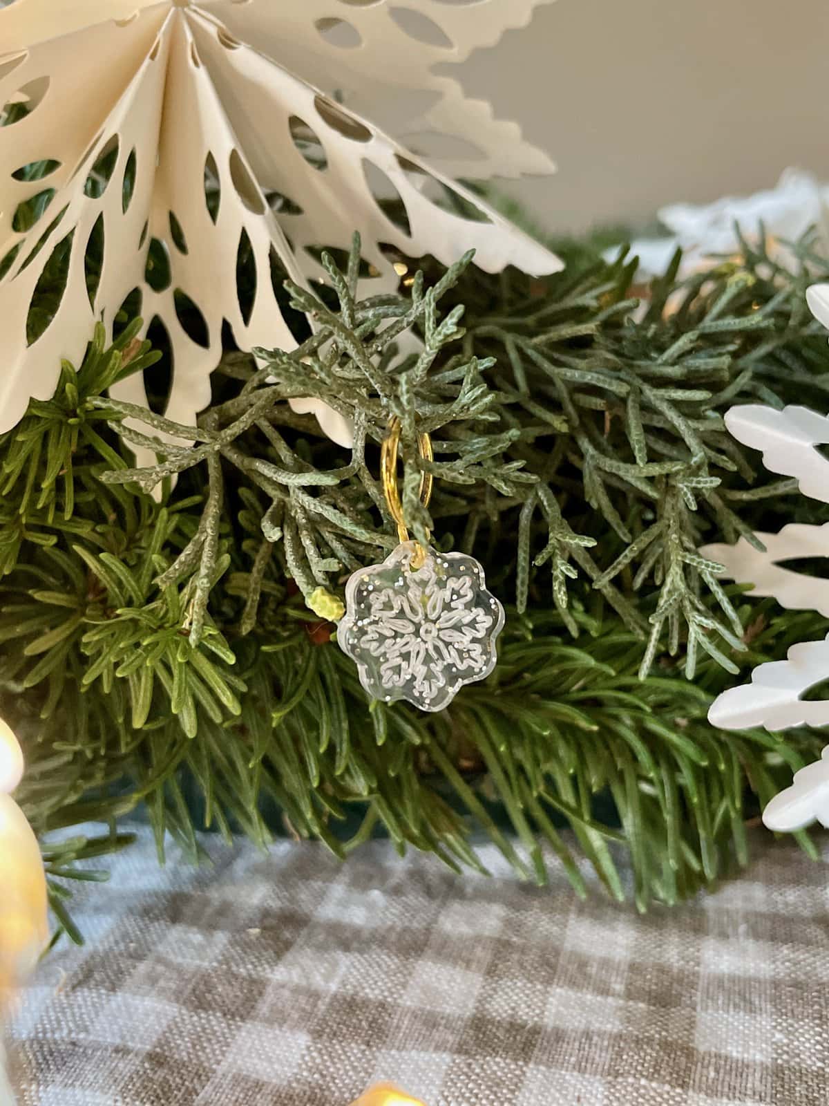 Bright winter-themed snowflake charm hanging on festive evergreen branches.
