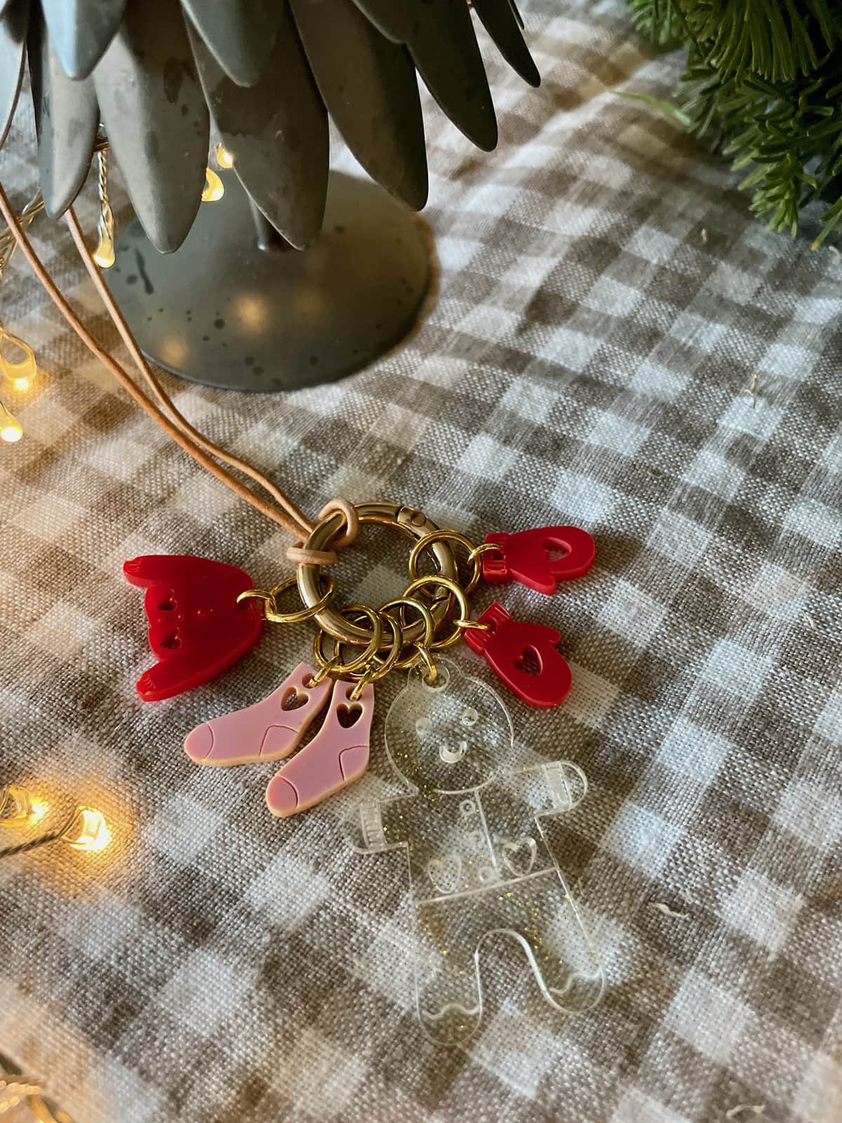Colorful acrylic baby-themed charm bracelet with red hearts, pink baby shoes, and a clear teddy bear on a checkered tablecloth.