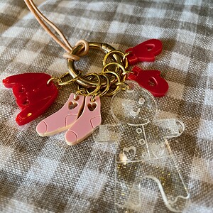 Colorful acrylic keychain charms on a gold ring with a pink strap.