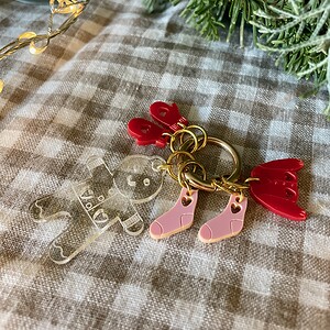 Colorful Christmas ornament keychain with baby sock, gingerbread bear, angel wings, and greenery.