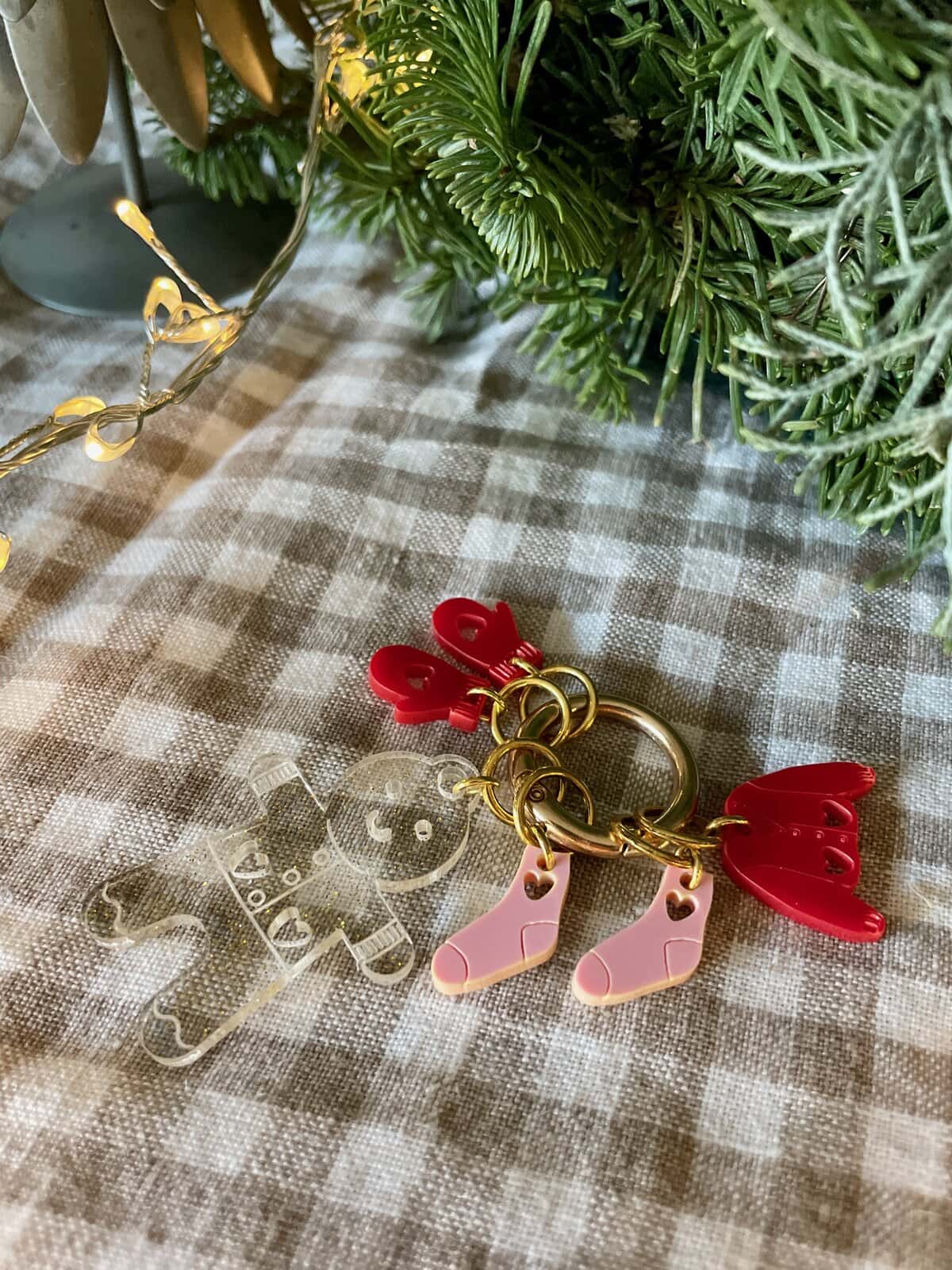 Colorful Christmas ornament keychain with baby sock, gingerbread bear, angel wings, and greenery.