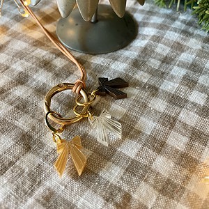 Delicate bow charm keychain with gold accents on checkered tablecloth for gift or accessory.