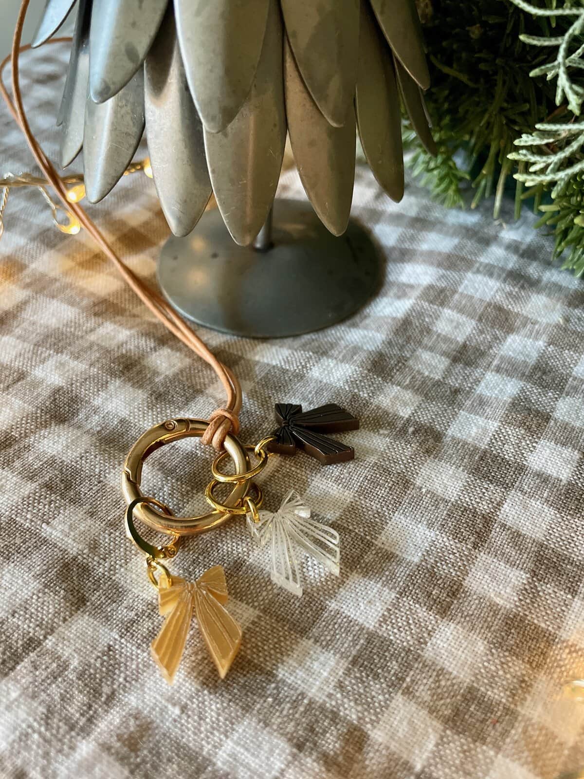Delicate bow charm keychain with gold accents on checkered tablecloth for gift or accessory.