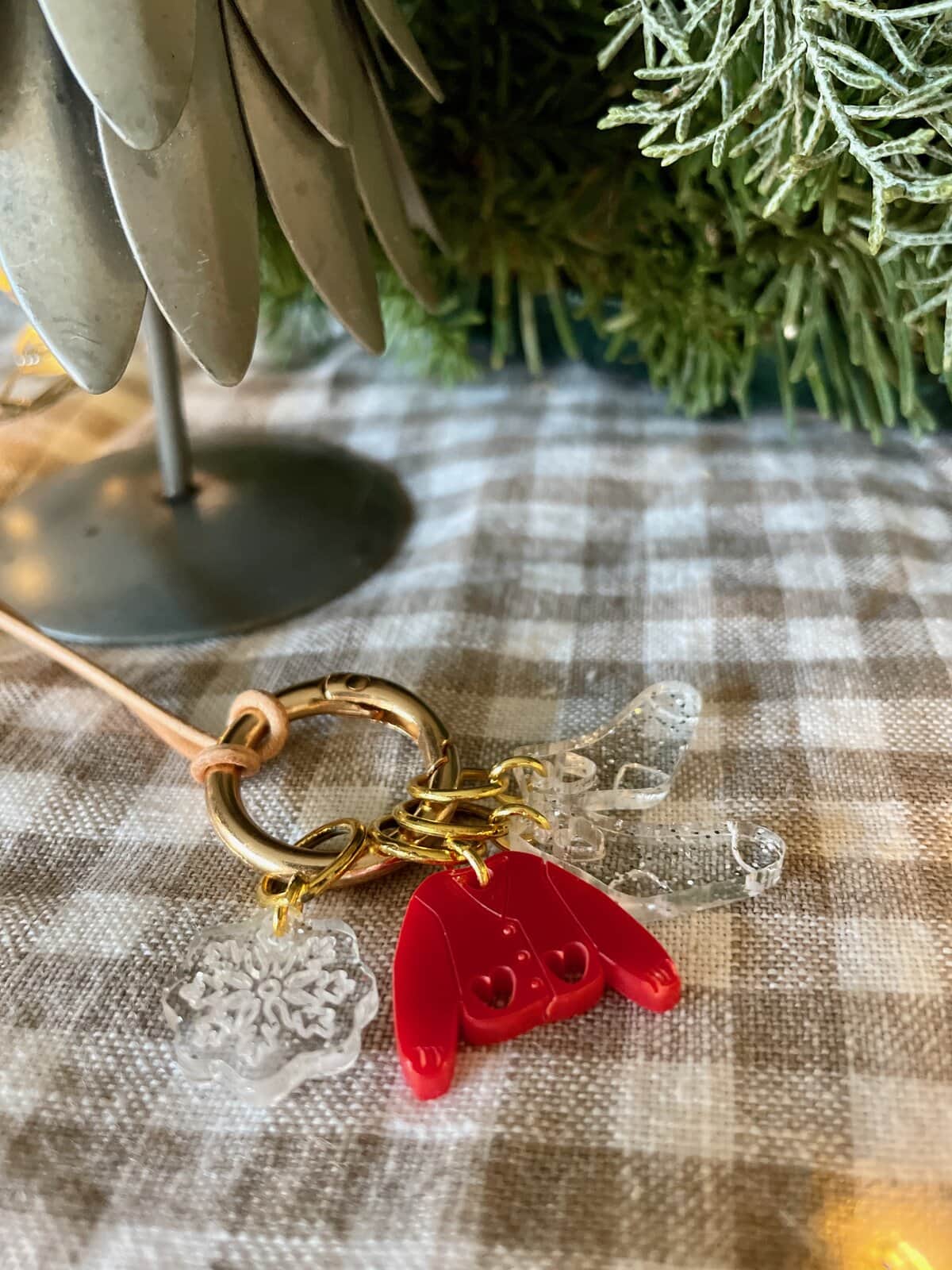 Colorful crochet hook keychain with clear snowflake and heart charms on checkered tablecloth, ideal for crochet enthusiasts.