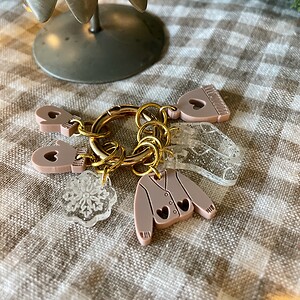 Soft pink plastic baby onesie keychain with snowflake charm and clear plastic teether, perfect for baby gifts and accessories.