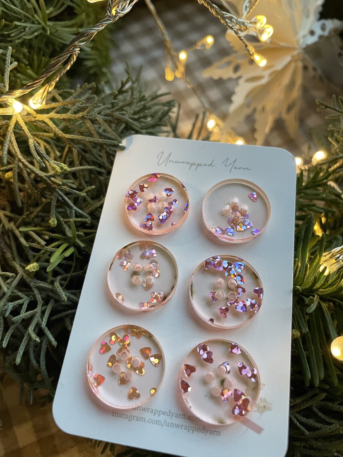 Sparkly resin button jewelry with pink and iridescent heart-shaped glitter. Perfect for festive craft projects and accessories.